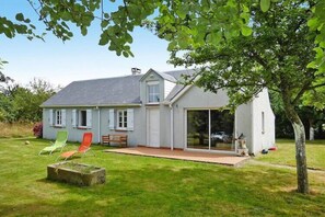 Une maison dotĂ©e dâun patio, dâune porte-fenĂȘtre coulissante et dâun petit jardin.