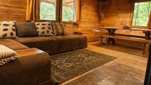 A log cabin interior with a sofa, a dining table, and a bench. - Great holiday home in the middle of nature and right on the lake, Natac Wielka (Natac Wielka)