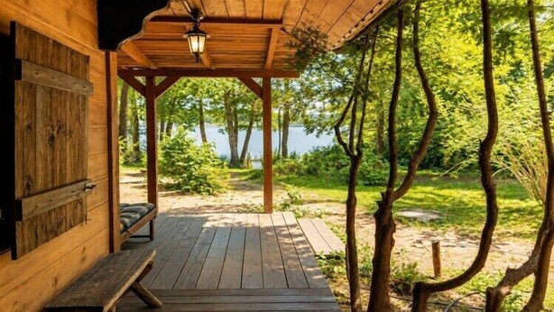 A wooden deck with a bench, a covered area with a lantern, and a view of trees and water. - Great holiday home in the middle of nature and right on the lake, Natac Wielka (Natac Wielka)