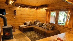 A cozy cabin interior with a wooden interior, a sofa, a table with apples, and a wood-burning stove. - Great holiday home in the middle of nature and right on the lake, Natac Wielka (Natac Wielka)