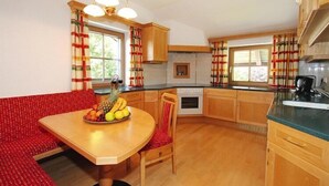 A kitchen with wooden cabinets, a dining table with a fruit bowl, and a red bench. - Apartment in Itter near Wilder Kaiser Ski Area (Itter)
