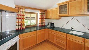 A kitchen with wooden cabinets, a black countertop, a window with curtains, and a sink. - Apartment in Itter near Wilder Kaiser Ski Area (Itter)