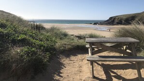 A beach with a wooden picnic table and a sandy path leading to the water. - Mounts Bay Inn (Helston)