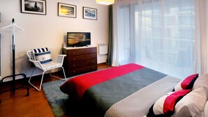 A hotel room with a bed, a chair, a dresser, and a television. - Apartment in Swinoujscie near the Beach (Swinoujscie)