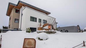 A modern building with a stone facade and a metal sculpture in front.
