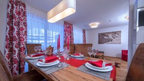 A dining area with a long wooden table set for four, red napkins, and candles.