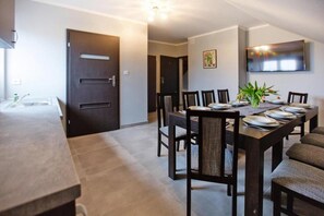 A dining area with a long table, chairs, and a television mounted on the wall.