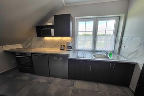 A compact kitchen with a dishwasher, a coffee maker, and a sink.