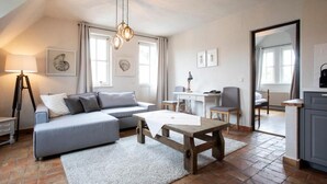 A cozy living room with a sofa, a coffee table, and a dining area with a table and chairs. - Landhaus Diedert (Wiesbaden)