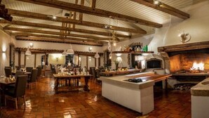 A spacious restaurant with a rustic interior, featuring exposed wooden beams, a brick floor, and a central island with a bar. - Landhaus Diedert (Wiesbaden)