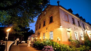 A historic building with a stone facade, outdoor seating area, and well-lit garden. - Landhaus Diedert (Wiesbaden)