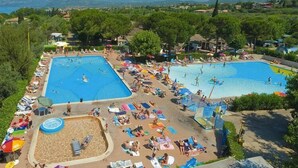 A resort with two swimming pools, a sandy beach area, and a view of the surrounding landscape. - Mobile home in Cisano San Vito caravan park (Cisano di Bardolino)