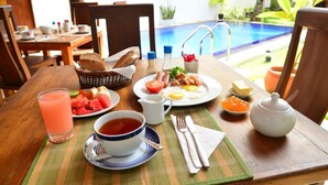 Una mesa de desayuno con diversos alimentos, un vaso de jugo, una taza de té y una tetera.