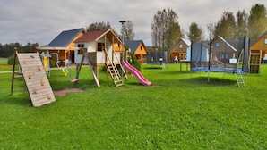 Ein Spielplatz mit Rutsche, Kletterwand und Trampolin.