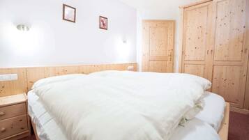 Een slaapkamer met een groot bed, een houten garderobe en twee wandlampen.