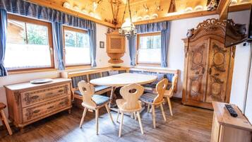 Een houten eetgedeelte met een ronde tafel en stoelen, een houten kast en een kroonluchter.