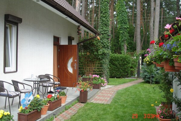 Una casa con puerta de madera, mobiliario exterior y plantas en macetas.