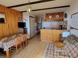 Una stanza accogliente con un tavolo da pranzo in legno, un divano, un angolo cottura con forno a microonde e una televisione.