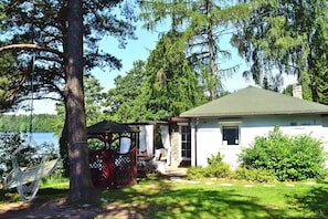 A house with a covered porch, a hammock, and a view of a lake.