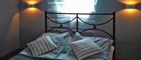 A bed with a metal headboard, two pillows, and two wall-mounted lights.