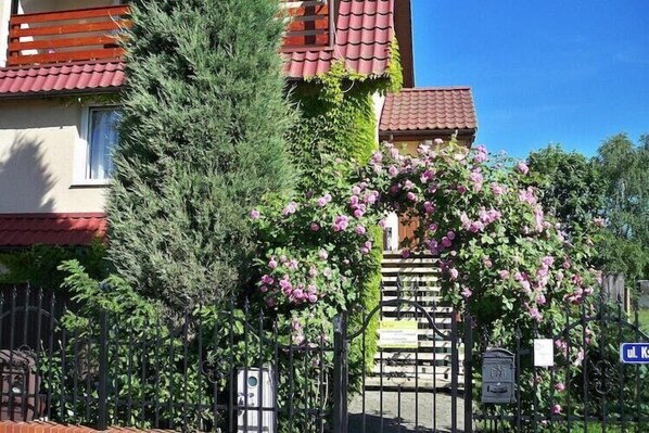 A building with a red-tiled roof, a wooden staircase, and a black metal fence.