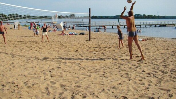 Partido de voleibol de playa con jugadores y espectadores.