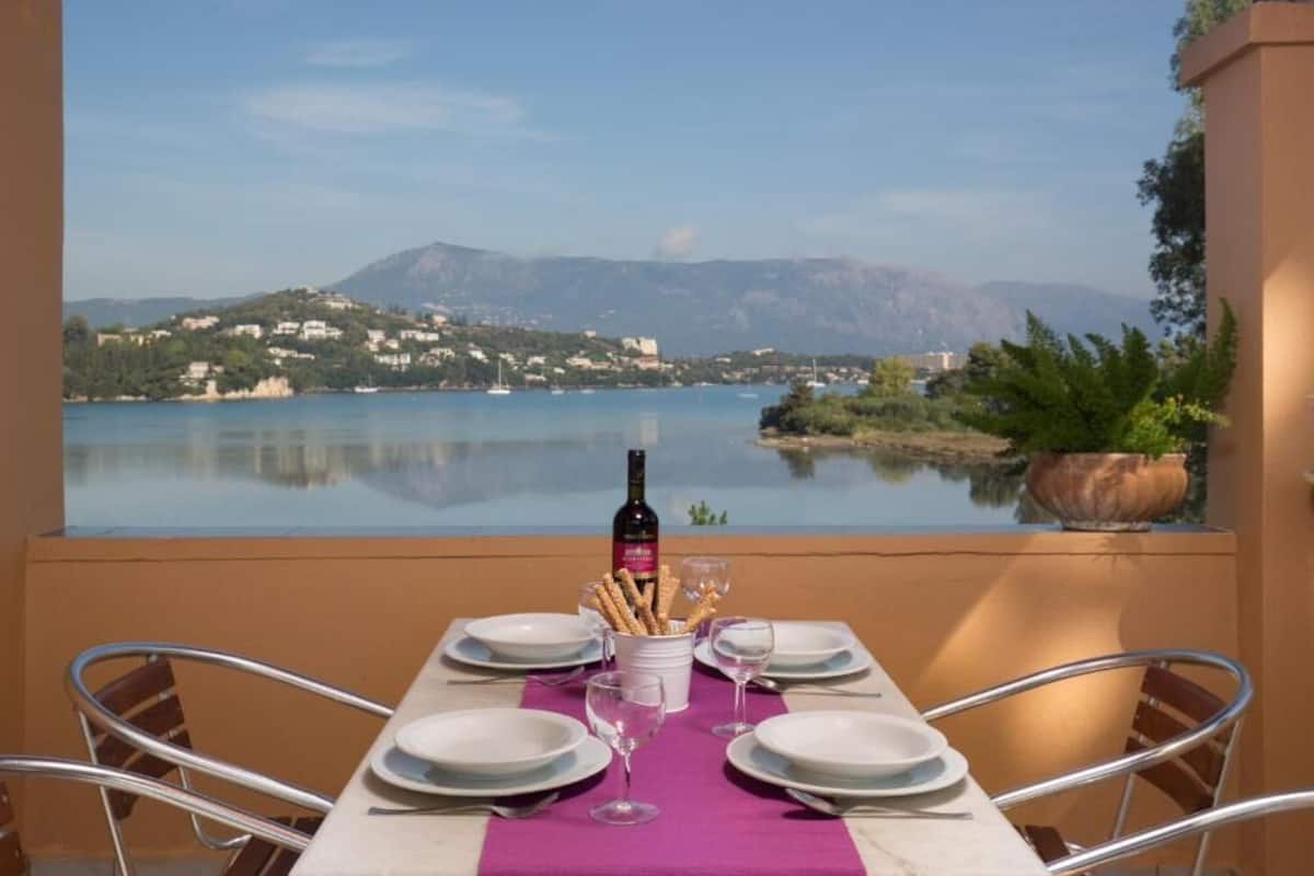 A table set for two with a view of a lake and mountains.