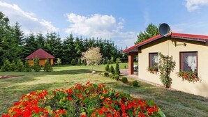 Una casa con techo rojo, antena parabólica y jardín con flores rojas.