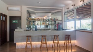 A bar area with stools, a counter, and a view of the outdoors. - Gerakini Poolside Holiday Apartment (Gerakini)