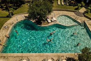 A swimming pool with multiple people swimming and lounging. - Gerakini Poolside Holiday Apartment (Gerakini)