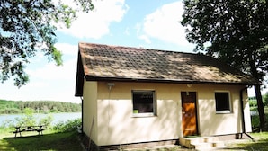 Una pequeña cabaña de un solo piso con tejado de tejas, una puerta principal y una ventana.
