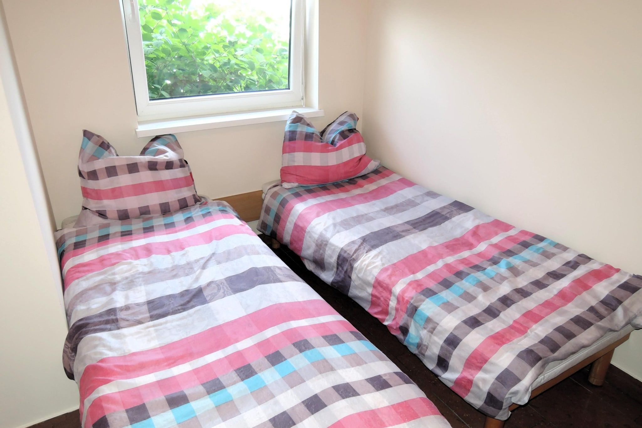 Une petite chambre avec deux lits simples, chacun recouvert d’une courtepointe à carreaux.