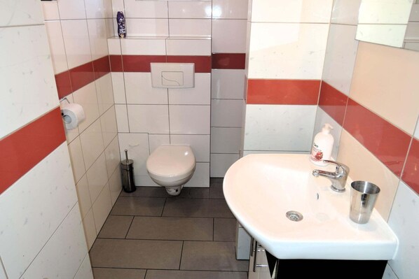 Un baño pequeño con inodoro, lavamanos y secador de manos.