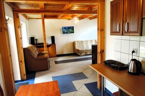 Un espacio de sala acogedor con un sofá, una mesa de centro y un televisor montado en la pared.
