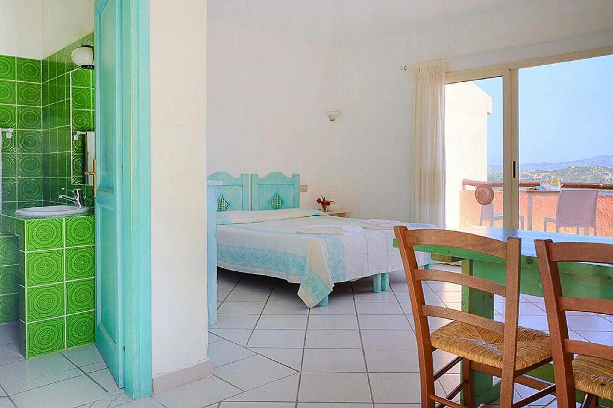 Une chambre avec un lit, une petite table, une chaise et un balcon avec vue.