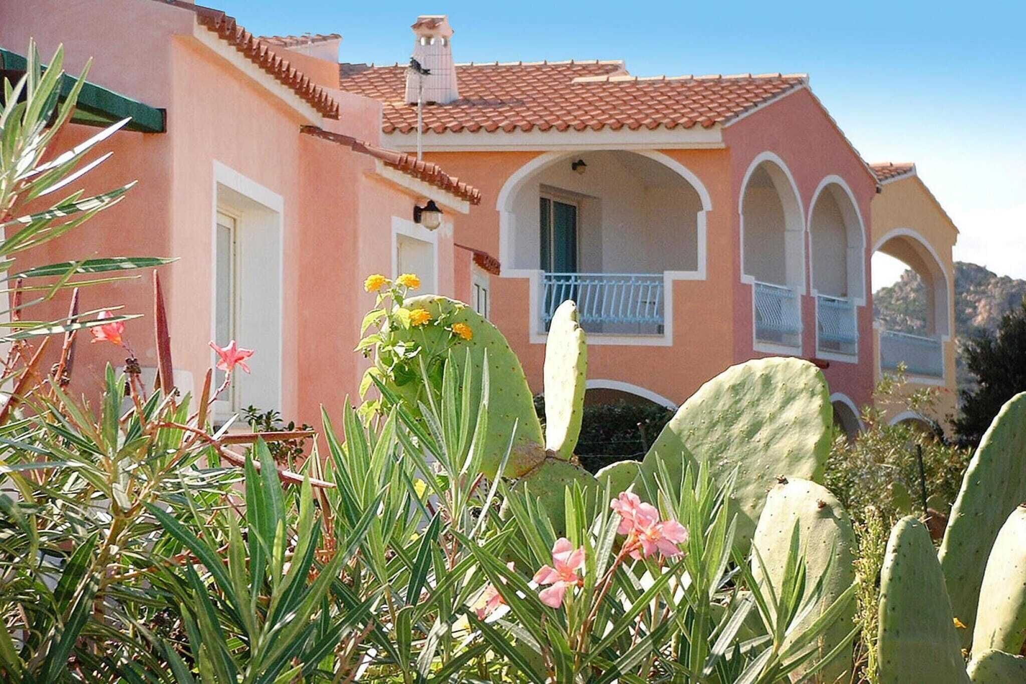 Un bâtiment rose avec un toit en tuiles, des fenêtres en arc de cercle et un balcon.