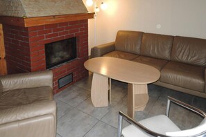 Un salon avec une cheminée en briques, un canapé en cuir et une table ronde.