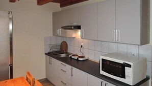 Eine kompakte Küche mit weißen Schränken, einer Mikrowelle, einem Spülbecken und einem Holzespeisetisch.
