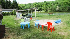 Ein Park mit einem überdachten Picknickbereich, einem See und Sitzgelegenheiten im Freien.