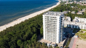 Un hotel de gran altura con varias plantas, vista al mar y un área boscosa cerca.