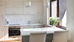 Una cocina moderna con armarios blancos, horno integrado, pileta y ventana con vista al exterior.