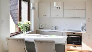 Una cocina moderna con armarios blancos, horno integrado y ventana con vista al techo.