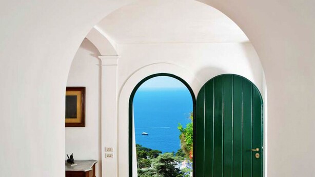 A hallway with an arched doorway leading to a view of the sea. - Villa Paradiso, Capri (capri)