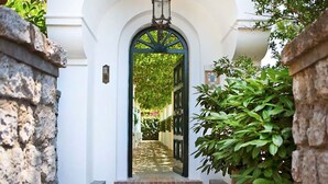 A white building with a green arched entrance, brick steps, and a lantern above the door. - Villa Paradiso, Capri (capri)