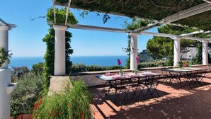 An outdoor patio with a table set for dining, overlooking a scenic view of the sea. - Villa Paradiso, Capri (capri)