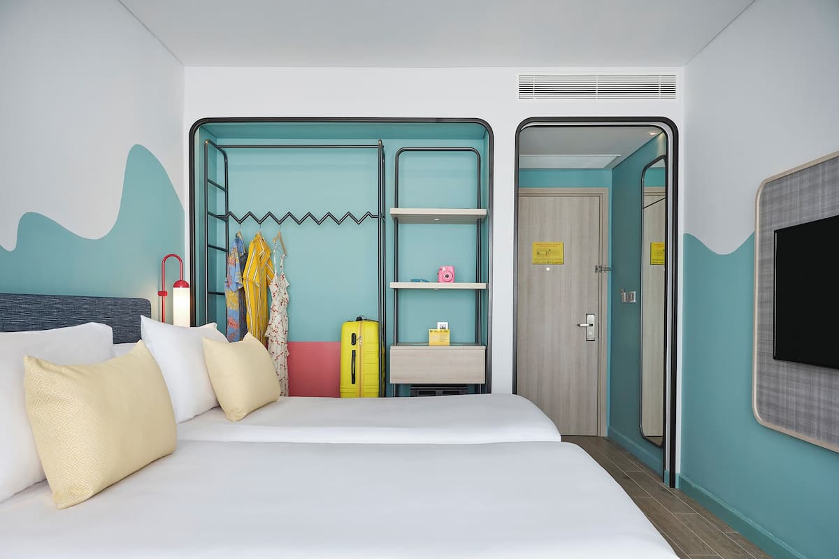 Ein Hotelzimmer mit Bett, Schrank, Schreibtisch und Fernseher.