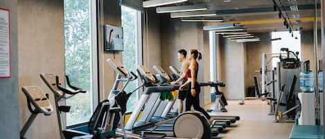 Un gimnasio con cintas de correr, elípticas y equipo de pesas.