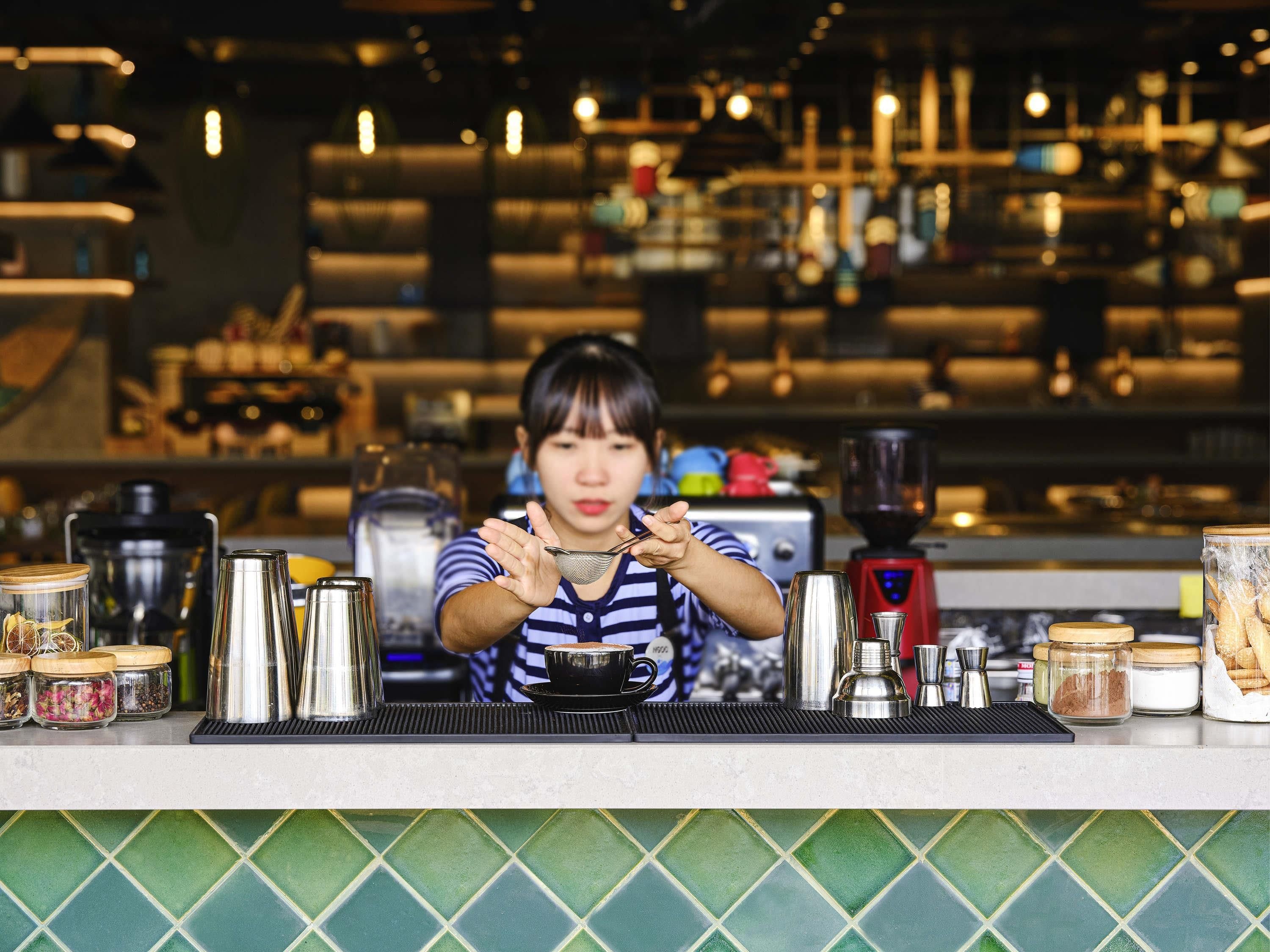 A barista at work in a kitchen with coffee-making equipment and ingredients.