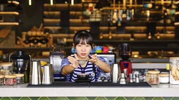 A barista at work in a kitchen with coffee-making equipment and ingredients.