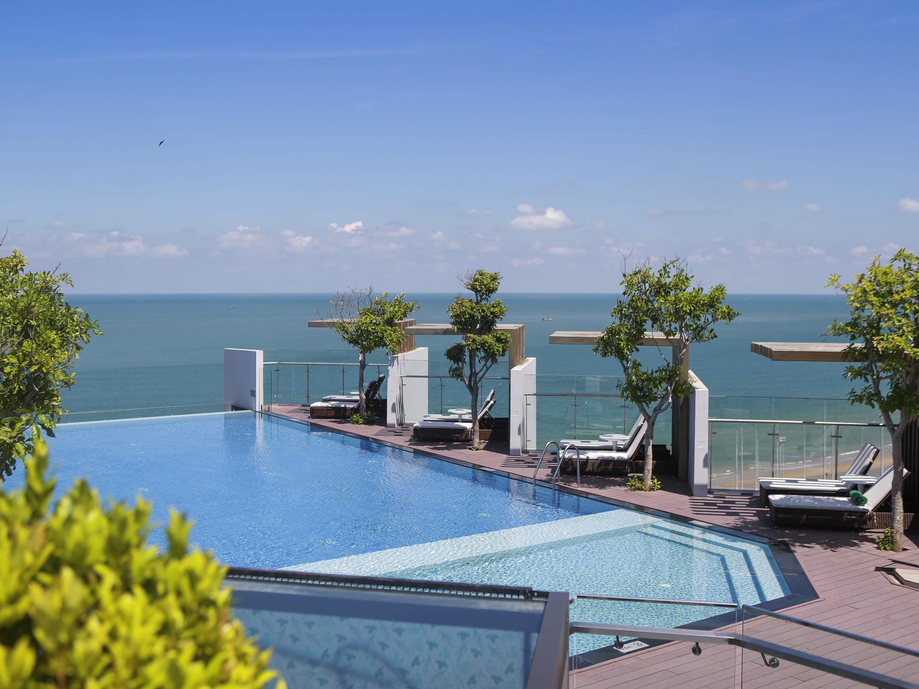 A rooftop infinity pool with lounge chairs and a view of the ocean.